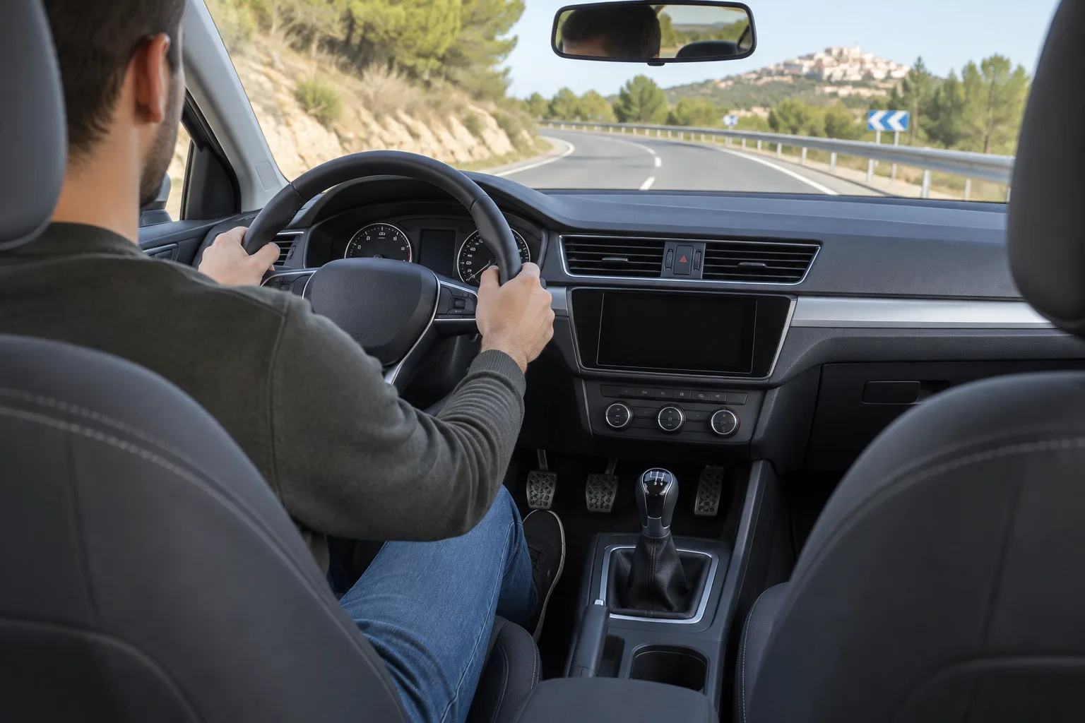 Interior de un coche con volante, pedales y palanca de cambios