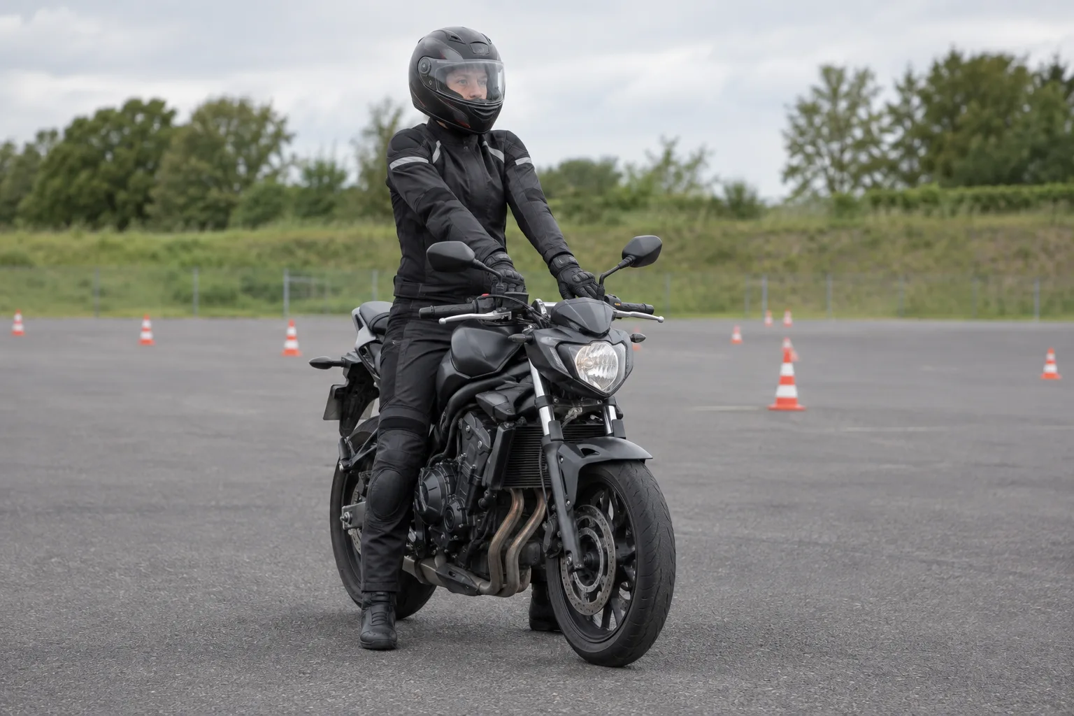 Motorista con casco muestra una postura forzada con brazos extendidos en una moto apagada