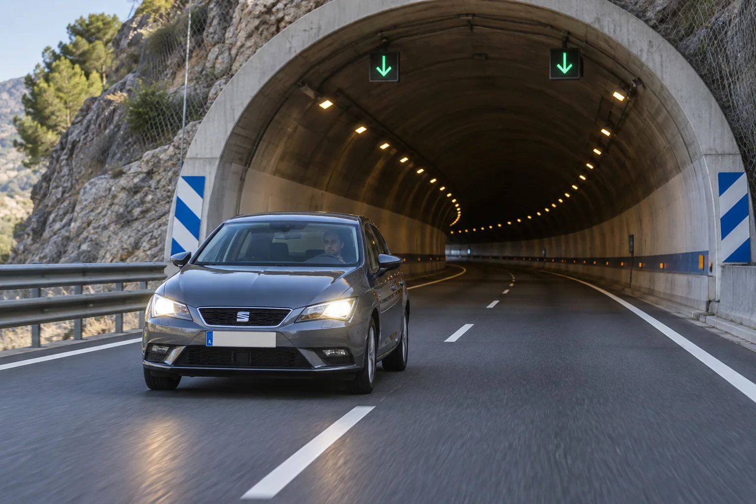 Coche con las luces encendidas mientras circula por un túnel durante el día