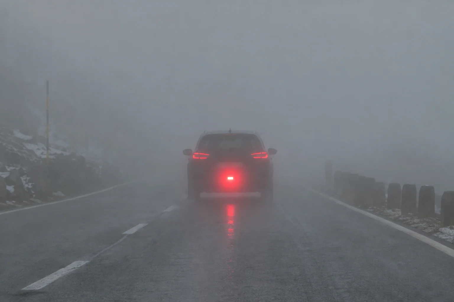 Parte trasera de un coche en niebla densa con la luz antiniebla roja visible
