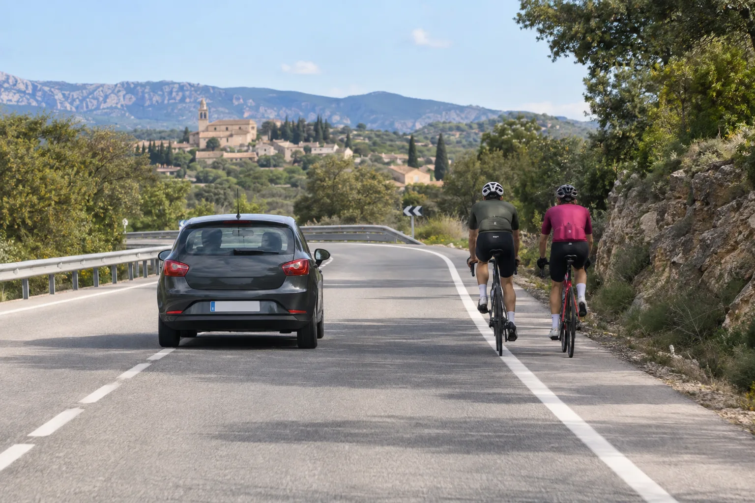 Ciclistas circulan por carretera mientras un coche mantiene separación lateral