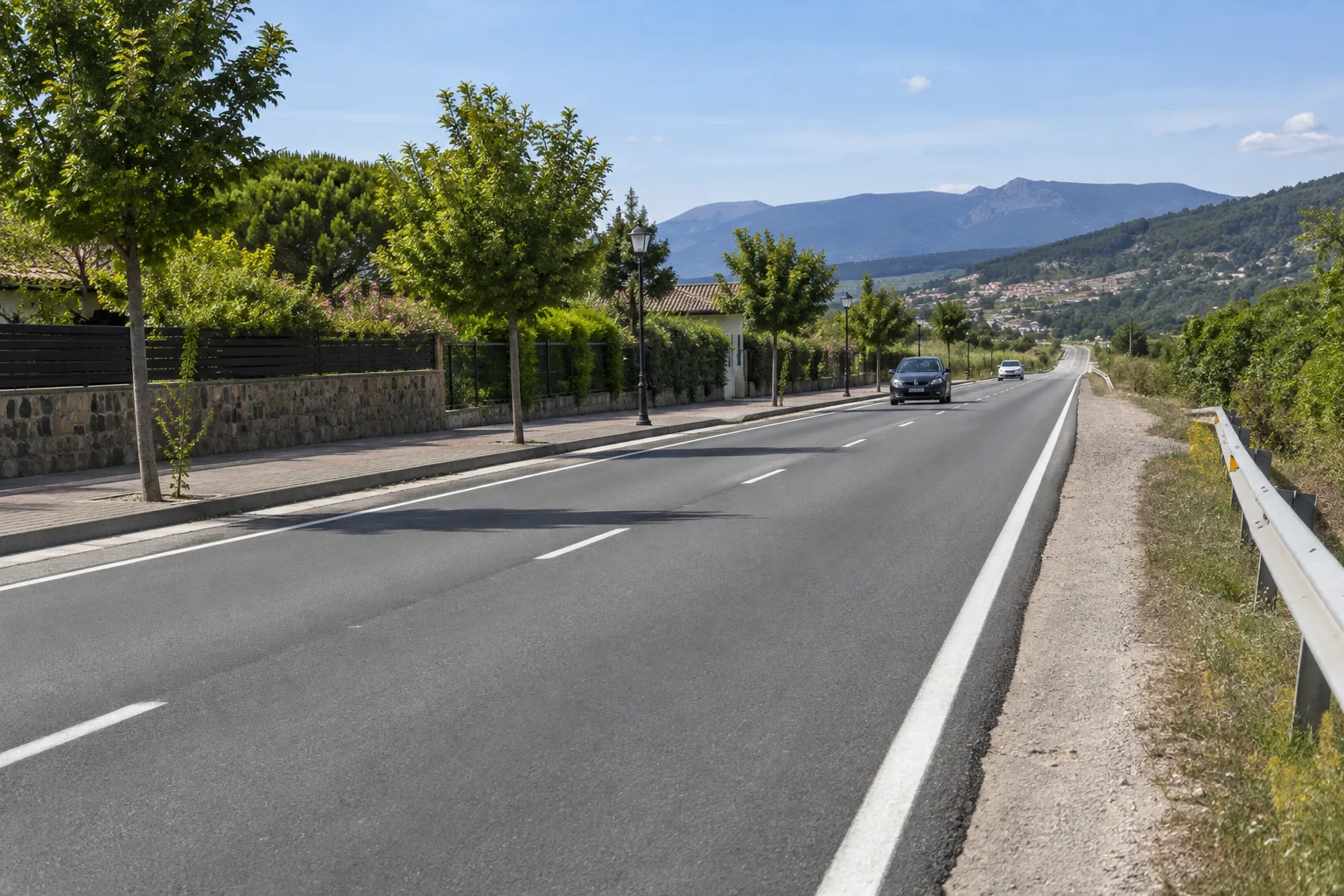 Carretera española con calzada, arcén y zona peatonal junto a un poblado
